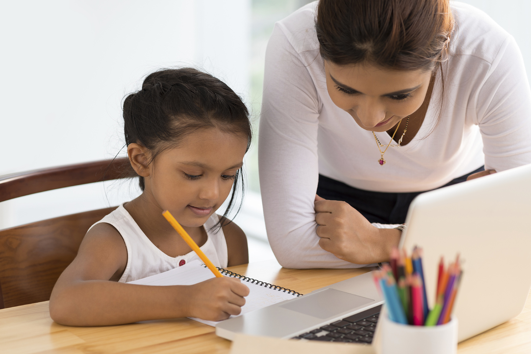 Young woman helping girl with her homework
